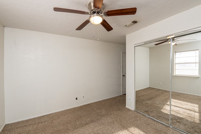 unfurnished bedroom featuring ceiling fan, carpet, a closet, and a textured ceiling