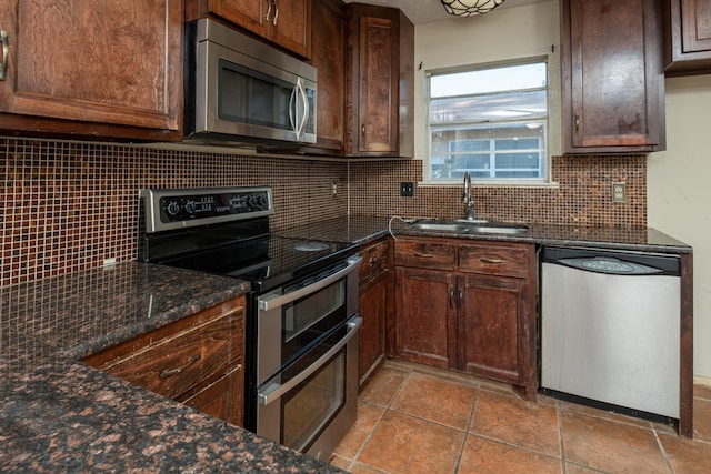 kitchen featuring appliances with stainless steel finishes, sink, dark stone counters, and decorative backsplash