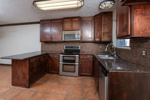 kitchen featuring appliances with stainless steel finishes, sink, a textured ceiling, and dark stone counters