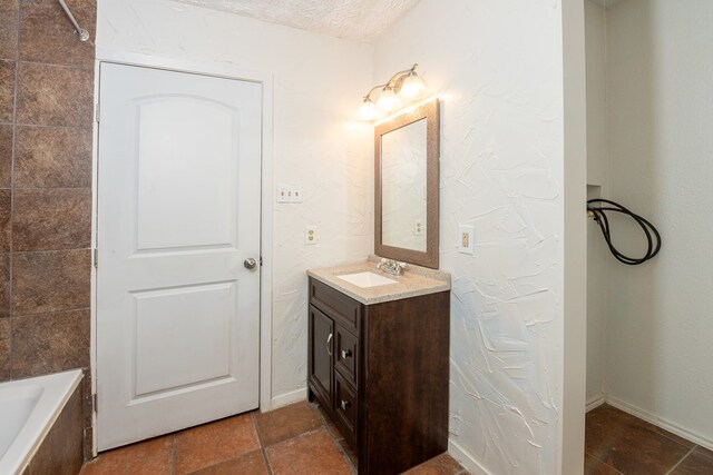 bathroom featuring vanity, a bathtub, and a textured ceiling