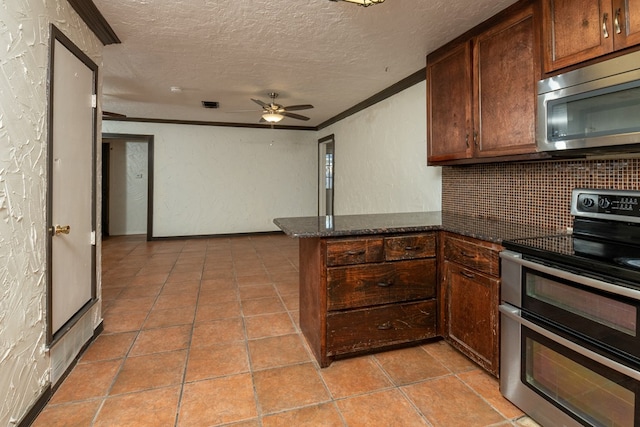 kitchen featuring appliances with stainless steel finishes, dark stone countertops, ornamental molding, a textured ceiling, and kitchen peninsula