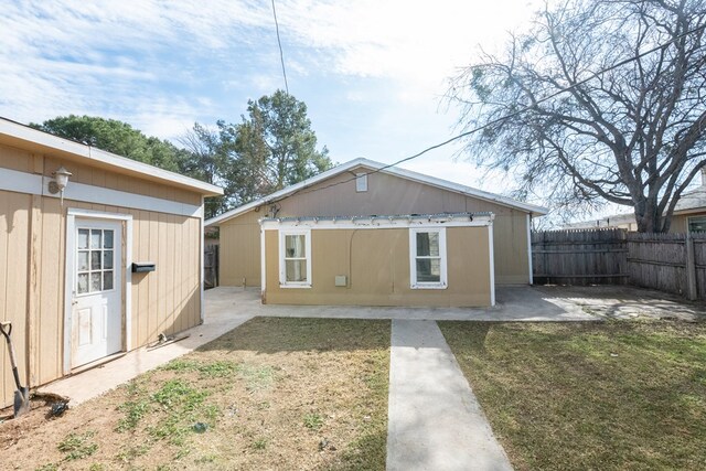 back of house with an outbuilding, a yard, and a patio area