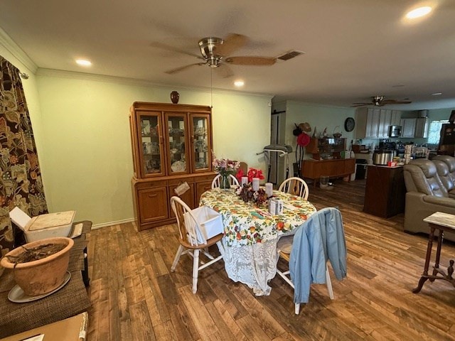 dining space featuring crown molding, wood finished floors, visible vents, and a ceiling fan