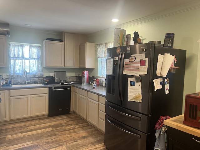 kitchen with ornamental molding, sink, wood-type flooring, and black appliances