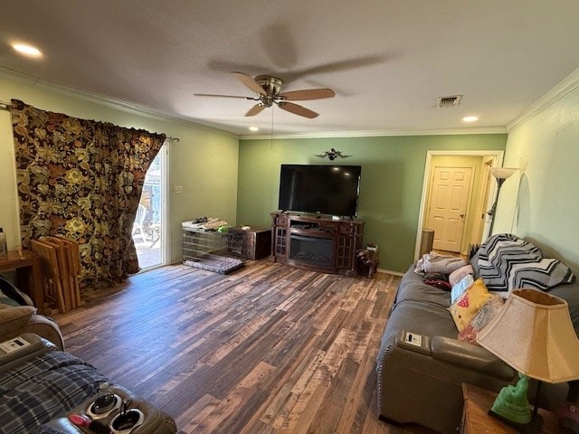 living area with visible vents, a ceiling fan, ornamental molding, wood finished floors, and a fireplace