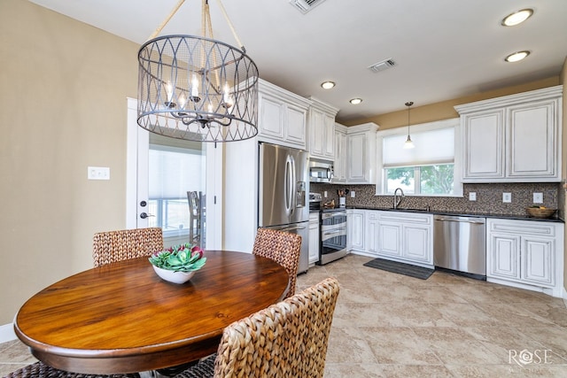 3045 Red Bluff Cir, San Angelo, TX 76904 - kitchen featuring appliances with stainless steel finishes, dark countertops, decorative backsplash, a chandelier, and decorative light fixtures