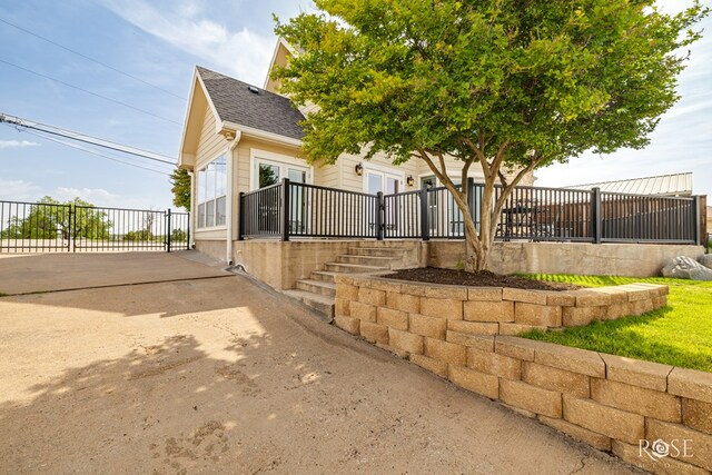 3045 Red Bluff Cir, San Angelo, TX 76904 - view of property exterior with fence, roof with shingles, concrete driveway, and french doors