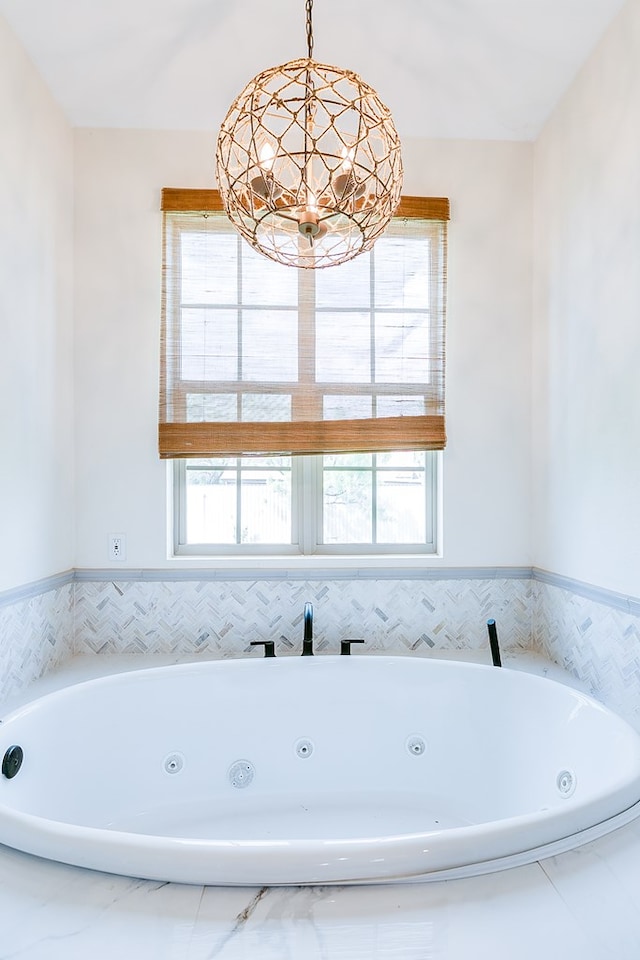 bathroom featuring a jetted tub and an inviting chandelier