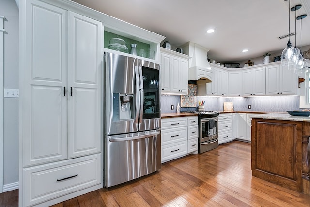 kitchen with premium range hood, appliances with stainless steel finishes, backsplash, and wood finished floors