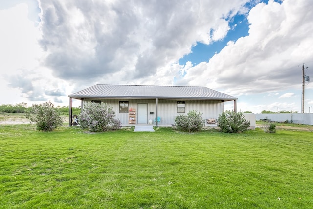 rear view of house featuring covered porch, metal roof, a lawn, and fence