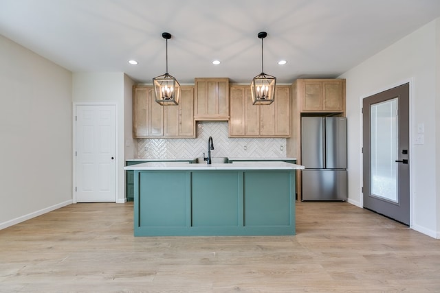 kitchen with light wood-type flooring, light countertops, a sink, and freestanding refrigerator