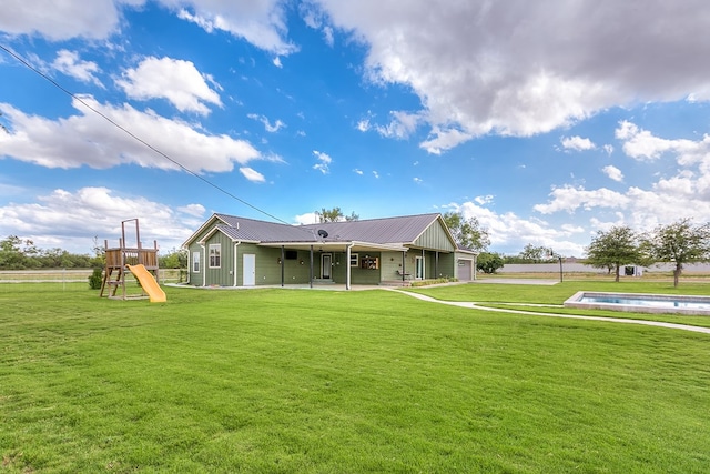 back of house featuring an outdoor pool, metal roof, playground community, and a lawn