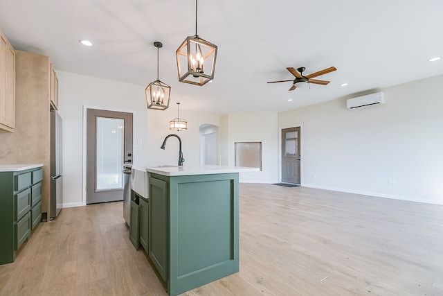 kitchen with a wall unit AC, freestanding refrigerator, light countertops, light wood-style floors, and green cabinets