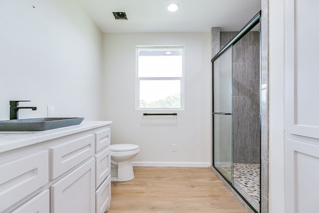 bathroom with a stall shower, baseboards, toilet, wood finished floors, and vanity