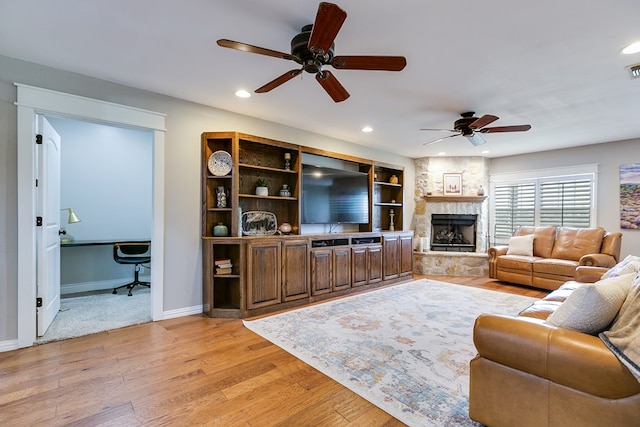 living area with a stone fireplace, recessed lighting, visible vents, baseboards, and light wood-type flooring