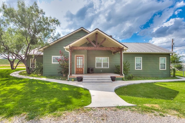 view of front of home featuring covered porch, metal roof, and a front yard