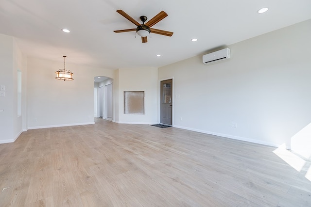 unfurnished room featuring arched walkways, a wall unit AC, light wood-style flooring, and recessed lighting