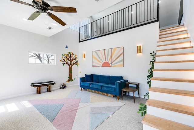 living room featuring baseboards, visible vents, a high ceiling, and stairs