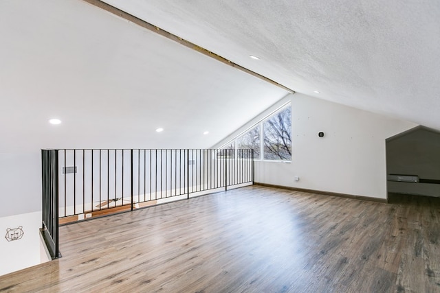 bonus room with vaulted ceiling with beams, a textured ceiling, baseboards, and wood finished floors