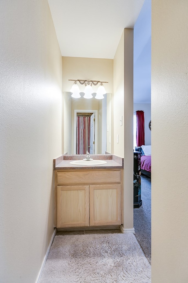 bathroom with ensuite bath, baseboards, and vanity