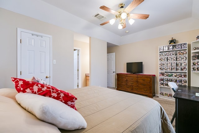 carpeted bedroom featuring visible vents, a raised ceiling, and a ceiling fan