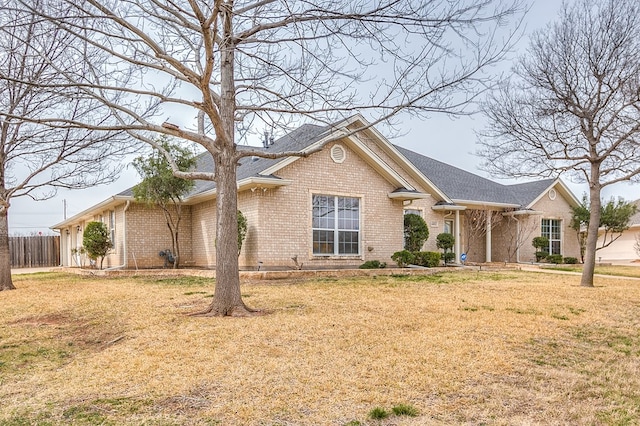 view of front of home with a front yard, brick siding, and fence