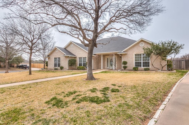 ranch-style home with brick siding, a front yard, and fence