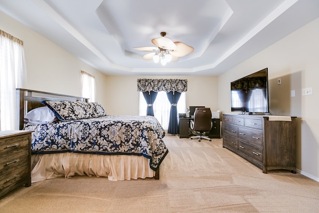 bedroom featuring light colored carpet, a raised ceiling, and multiple windows