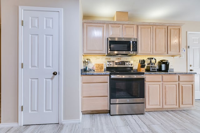 kitchen with baseboards, stainless steel appliances, light brown cabinetry, and tasteful backsplash