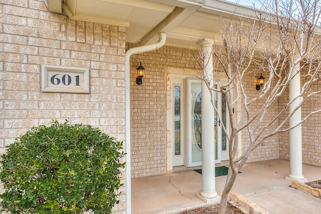 doorway to property with covered porch and brick siding