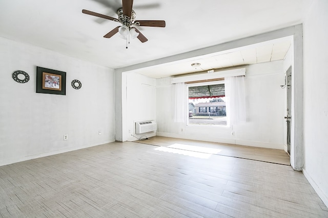 empty room with light wood-type flooring, a wall mounted AC, and ceiling fan