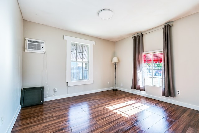 empty room with a wall mounted air conditioner and dark hardwood / wood-style floors