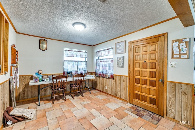 dining area with crown molding, a textured ceiling, and wood walls