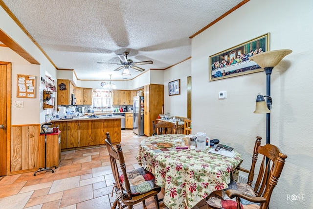 dining space with a textured ceiling, ornamental molding, ceiling fan, and wood walls