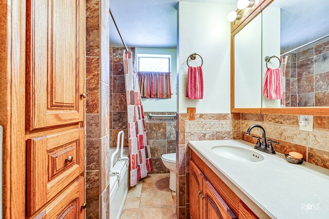 full bathroom featuring shower / bath combo, tile walls, vanity, and toilet