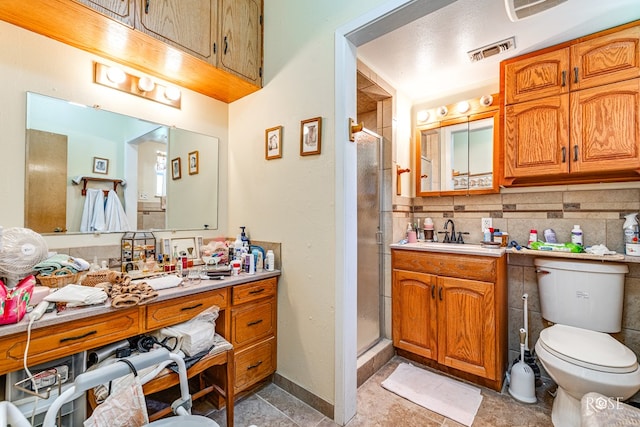 bathroom featuring vanity, toilet, backsplash, and a shower with shower door