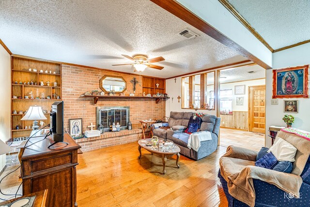 living room featuring hardwood / wood-style floors, wooden walls, ornamental molding, ceiling fan, and a textured ceiling