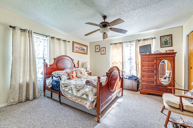 carpeted bedroom featuring ceiling fan and a textured ceiling