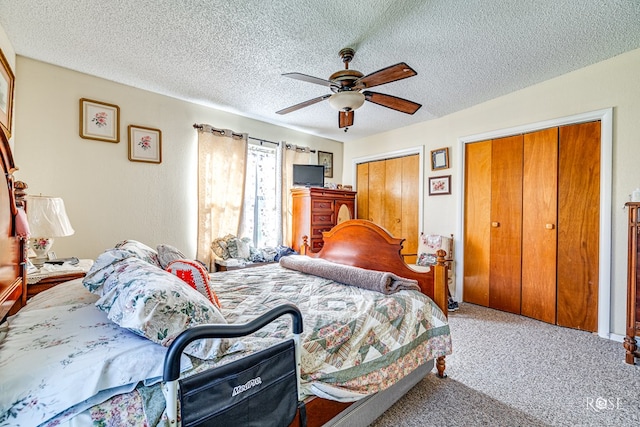 carpeted bedroom with two closets, a textured ceiling, and ceiling fan