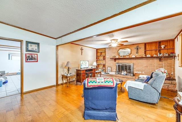 living room with built in shelves, a brick fireplace, a textured ceiling, light hardwood / wood-style flooring, and ceiling fan