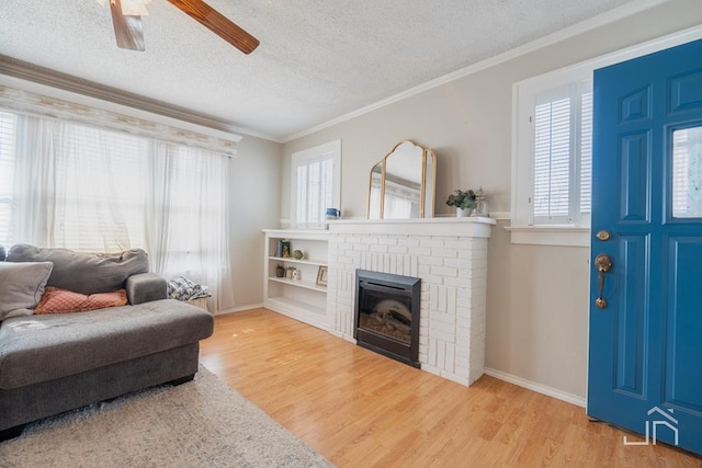 living room with a fireplace, a textured ceiling, crown molding, and wood finished floors