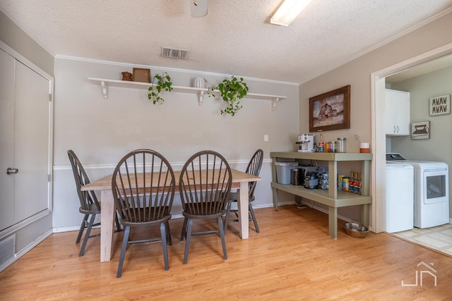 dining room featuring visible vents, independent washer and dryer, crown molding, and light wood finished floors