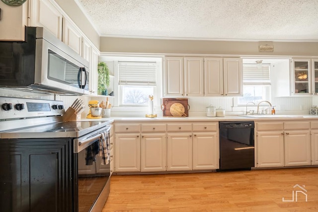 kitchen featuring light wood finished floors, a sink, stainless steel appliances, light countertops, and a textured ceiling