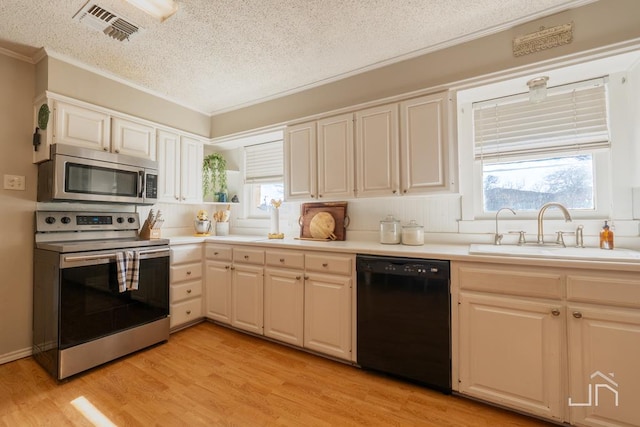 kitchen with visible vents, light wood-type flooring, a sink, appliances with stainless steel finishes, and a healthy amount of sunlight