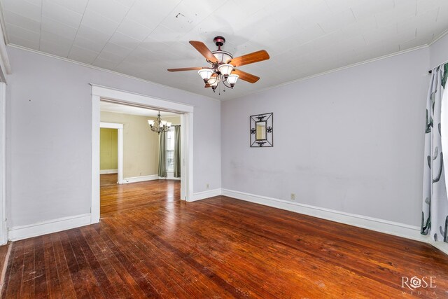 spare room featuring hardwood / wood-style floors, ceiling fan with notable chandelier, and ornamental molding