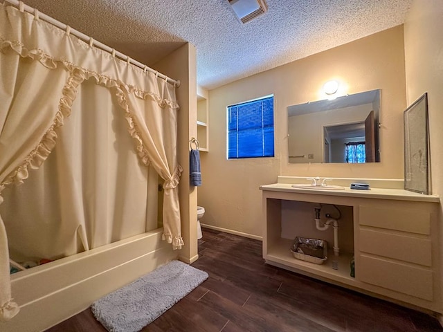 full bathroom with shower / tub combo with curtain, toilet, sink, and a textured ceiling