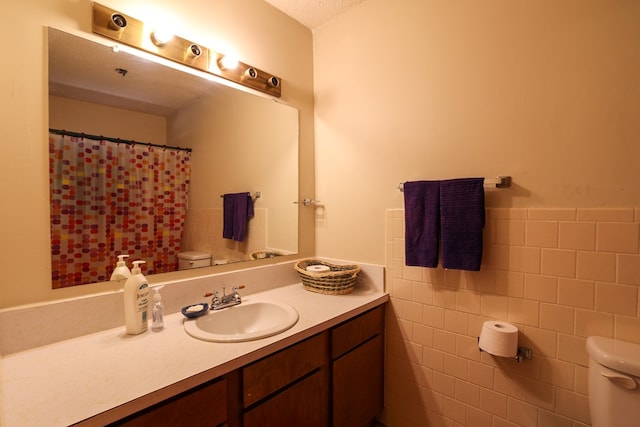 bathroom with vanity, toilet, and tile walls