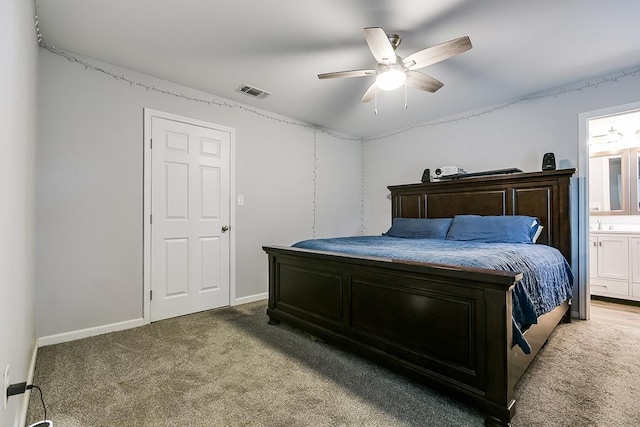 carpeted bedroom featuring a ceiling fan, ensuite bath, visible vents, and baseboards