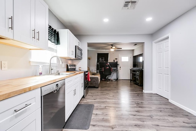 kitchen featuring light wood finished floors, visible vents, appliances with stainless steel finishes, white cabinetry, and a sink