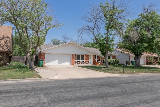 ranch-style house with fence, brick siding, a garage, a front yard, and concrete driveway